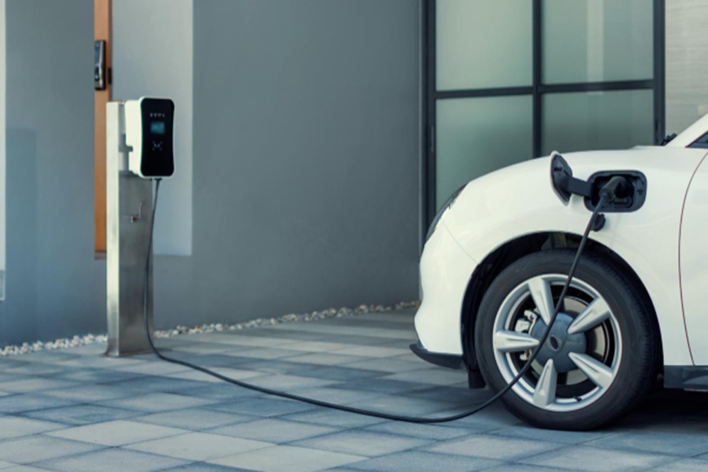 Weißes Elektroauto lädt an freistehender Wallbox in moderner Einfahrt, komfortable Ladelösung von Hanse Energietechnik.